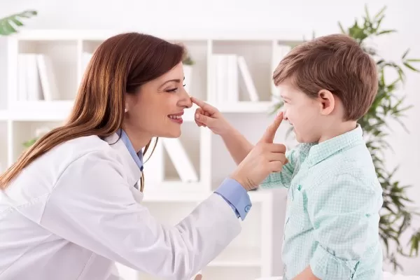 imagem de uma mae abaixada tocando com o dedo indicador o nariz de seu filho que tambem esta tocando no nariz dela