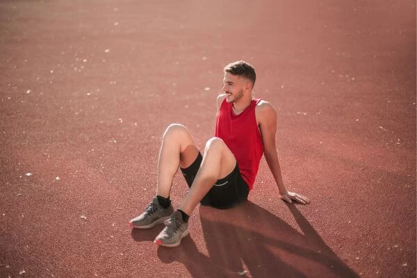 imagem de um homem sentado no chão descansando feliz após ter feito uma corrida