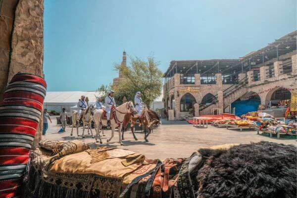 imagem de árabes cavalgando em uma vila e transportando produtos para comércio